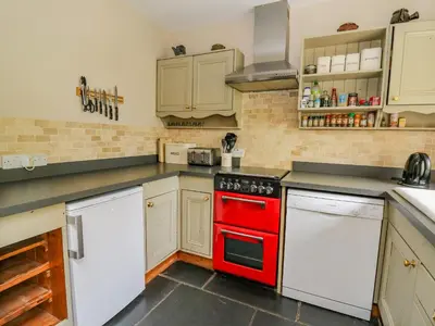 a kitchen with a red oven and white appliances at Byrdir Cottage in Llanwrthwl