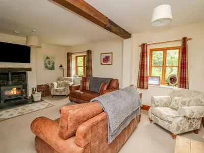 a living room filled with furniture and a fireplace at Byrdir Cottage in Llanwrthwl