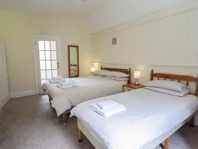 a room with three beds with white sheets at Bryn Cemlyn in Llanfachreth