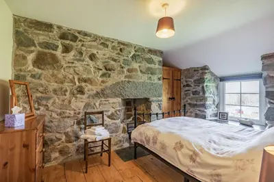 a bedroom with a stone wall and a bed at Ty Capel Jeriwsalem in Trawsfynydd