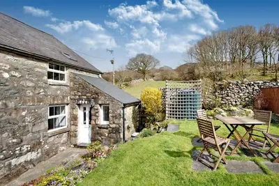 an old stone house with a table and a garden at Ty Capel Jeriwsalem in Trawsfynydd