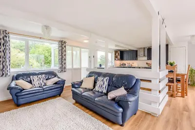 a living room with two blue leather couches and a kitchen at Penty in Dolgellau