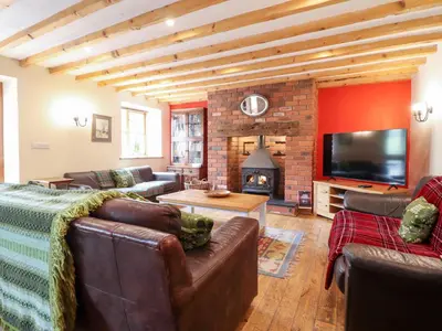 a living room with leather furniture and a fireplace at Ysgubor Pwlliago in Pennant-Melangell