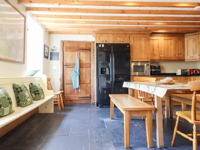 a kitchen with wooden cabinets and a table and chairs at Ysgubor Pwlliago in Pennant-Melangell