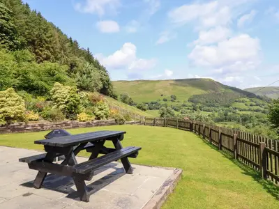 a picnic table with a view of the mountains at Ysgubor Pwlliago in Pennant-Melangell