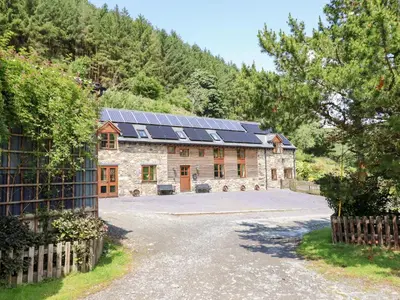 an exterior view of a stone house with solar panels at Ysgubor Pwlliago in Pennant-Melangell