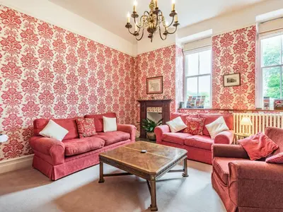 a living room with red couches and a table at Pensarn Hall in Llanbedr