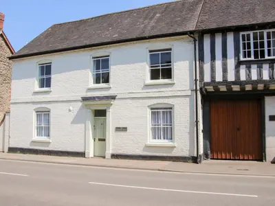 a white brick house with a wooden door on a street at The Maltster's House in Ludlow
