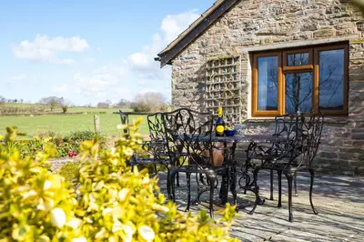 a table and chairs in front of a stone cottage at Stargazer's Field House in Clifford