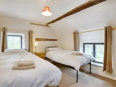 two beds in a room with two windows at The Birches in Craswall
