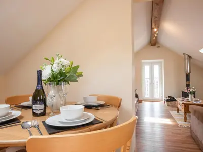 a dining room with a table with a bottle of wine at Hendre Cottage in Trawsfynydd