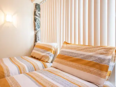 a bed with two pillows sitting next to a window at Hendre Cottage in Trawsfynydd