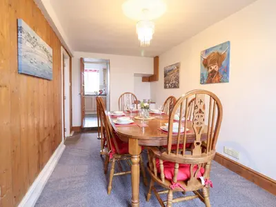 a dining room with a wooden table and chairs at Bryn Re in Trawsfynydd