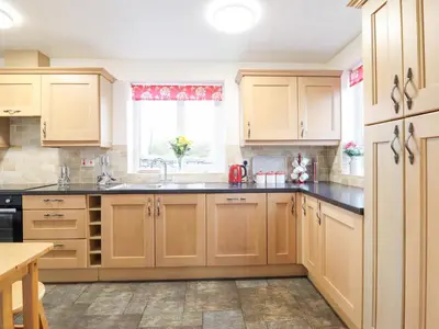 a kitchen with wooden cabinets and a window at Bryn Re in Trawsfynydd