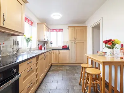 a kitchen with wooden cabinets and a island with stools at Bryn Re in Trawsfynydd