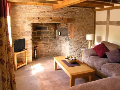 a living room with a couch and a table at Point Cottage in Blakemere
