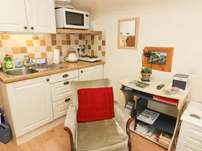 a kitchen with a chair and a sink and a microwave at Beacons Rest in Llanspyddid