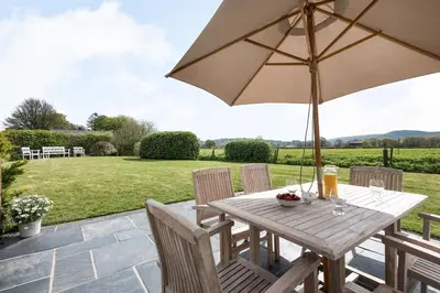a wooden table with an umbrella on a patio at 2 Siluria Cottage in New Radnor