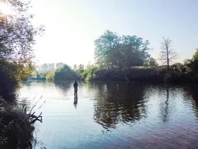 a person is standing in the middle of a river at Herons in Byford