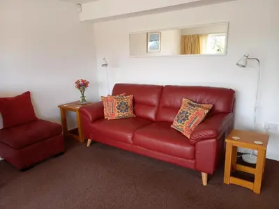 a living room with a red couch and a chair at Herons in Byford