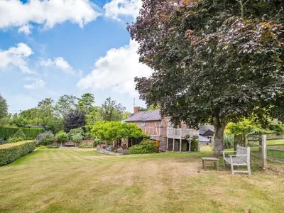 an old house with a tree and a bench in the yard at The Cider Mill in Kings Pyon