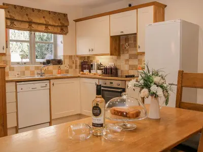 a kitchen with a table with a bottle of wine and a bread at The Turnip House in Acton Scott