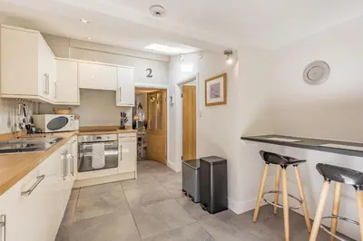 a kitchen with white cabinets and two bar stools at 2 Bryn Tirion in Tanygrisiau