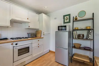 a kitchen with white cabinets and a refrigerator at Gorwel in Blaenau-Ffestiniog