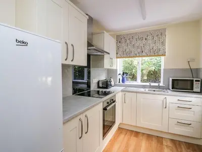 a white kitchen with white cabinets and a window at Salmon Cottage in Llanwrthwl
