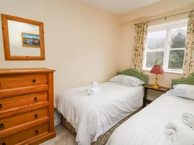 two beds in a bedroom with a dresser and a mirror at Salmon Cottage in Llanwrthwl