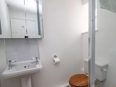 a white bathroom with a sink and a toilet at Salmon Cottage in Llanwrthwl