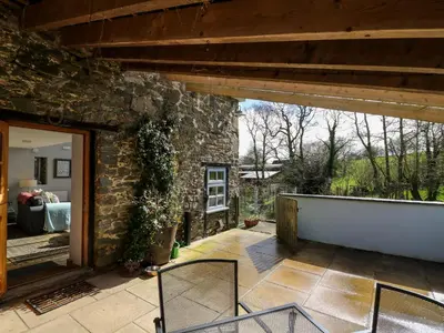 a patio with chairs and a stone building at The Barn at Glanoer in Bettws Disserth