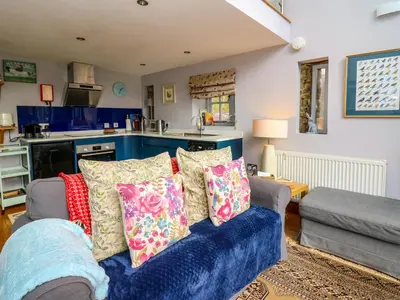 a living room with a blue couch with pillows at The Barn at Glanoer in Bettws Disserth