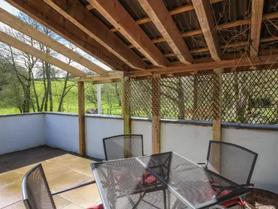 a patio with a glass table and chairs on a porch at The Barn at Glanoer in Bettws Disserth