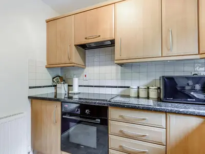 a kitchen with wooden cabinets and a black oven at Llety Nest in Llanfachreth