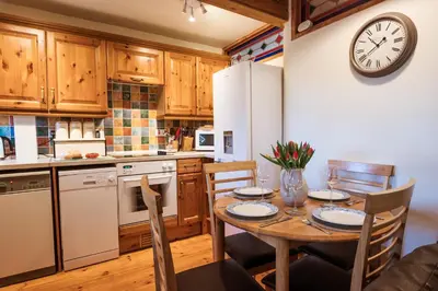 a kitchen with a table and a clock on the wall at Stabal Cottage in Cross Foxes