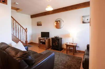 a living room with a leather couch and a television at Stabal Cottage in Cross Foxes