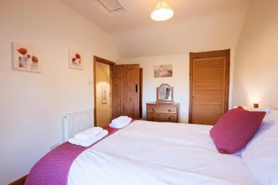 a bedroom with a large white bed with two towels on it at Stabal Cottage in Cross Foxes