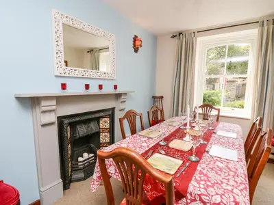 a dining room with a table and a fireplace at Derwen Villa in Mydroilin