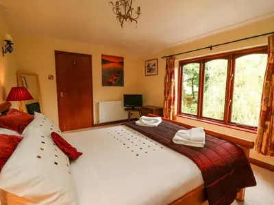 a bedroom with a large bed and a window at Derwen Villa in Mydroilin