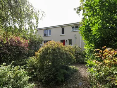 a building is seen through a garden of bushes at Derwen Villa in Mydroilin