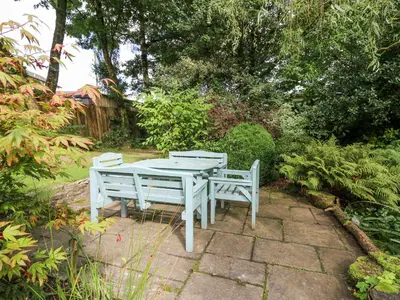 a picnic table and two benches sitting in a garden at Derwen Villa in Mydroilin