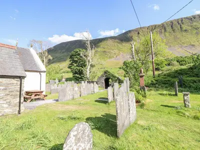 a group of gravestones in a cemetery with a building at St Mary's in Tal-y-llyn