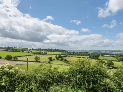 a view of a green field with trees and clouds at Hope Hall Barn in Bromlow