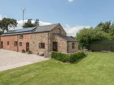 an old brick building with a grass yard at Hope Hall Barn in Bromlow