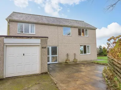 a large brick house with a white garage at The Villa in Harlech