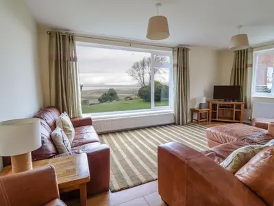 a living room with a couch and a large window at The Villa in Harlech