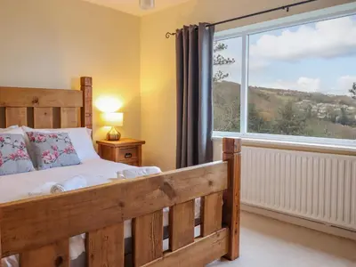 a bedroom with a wooden bed and a large window at The Villa in Harlech