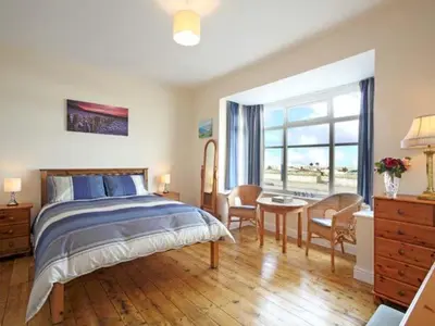 a bedroom with a bed and a desk and a window at Trysor Y Mor in Borth