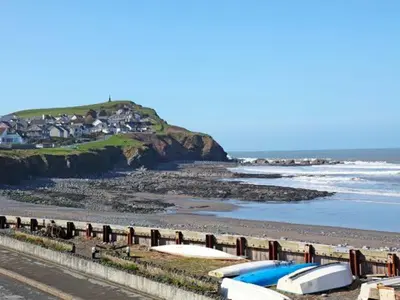 a beach with boats on the sand and a house at Trysor Y Mor in Borth